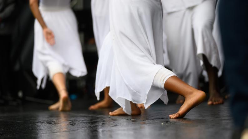 Des danseuses en robes blanches fluides se produisent pieds nus sur scène lors d’une danse contemporaine gracieuse