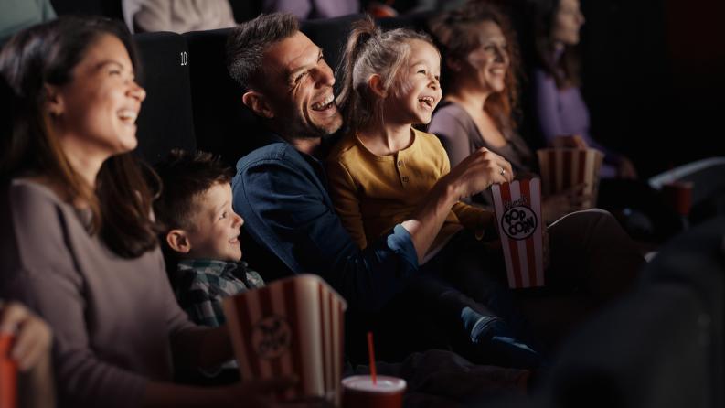 Famille joyeuse regardant un film drôle au théâtre