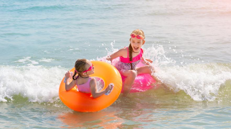 Deux petites sœurs jouent et s’amusent dans l’eau de mer sur la plage