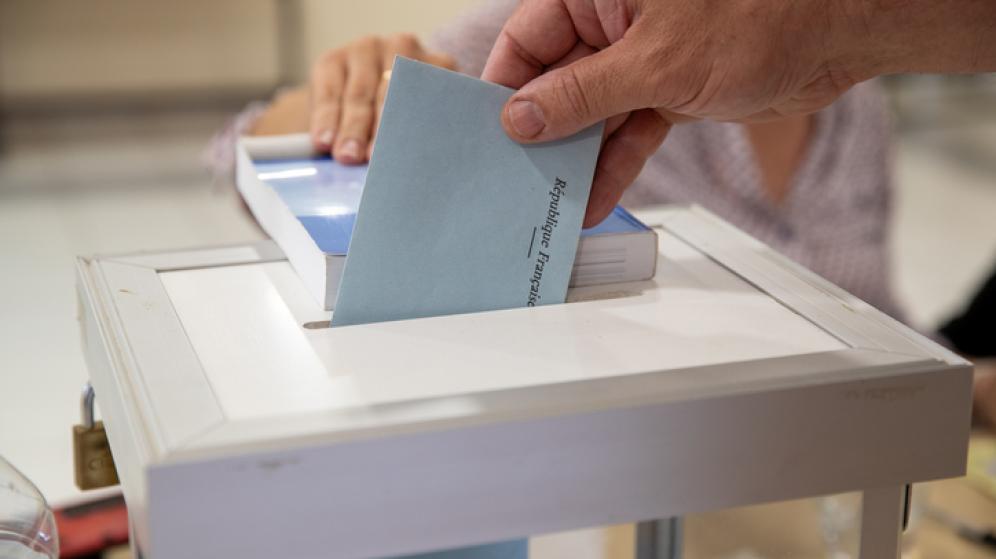 Vue de la main d’un homme déposant son bulletin de vote dans l’urne