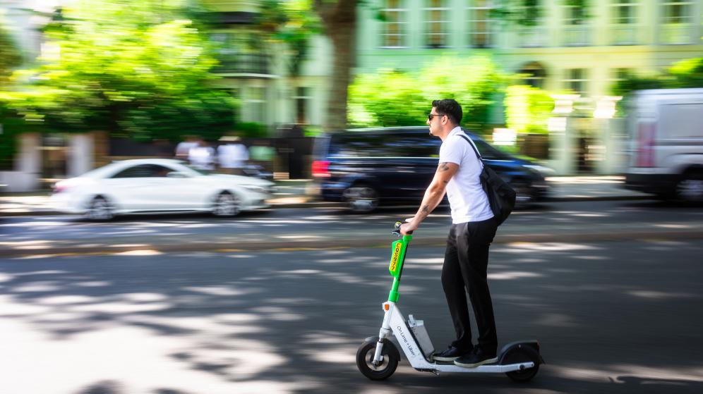 un homme circule en ville sur une trottinette électrique