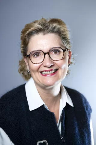 Une femme blonde qui sourit avec des lunettes