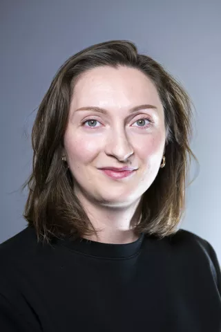 Une jeune femme brune aux yeux verts sourit à l'écran