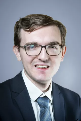 Un homme châtain clair sourit à l'écran