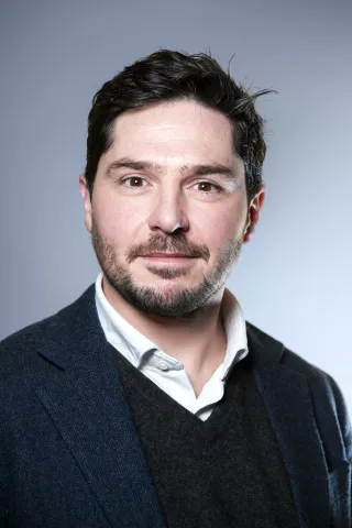 Un homme brun regarde fixement l'objectif