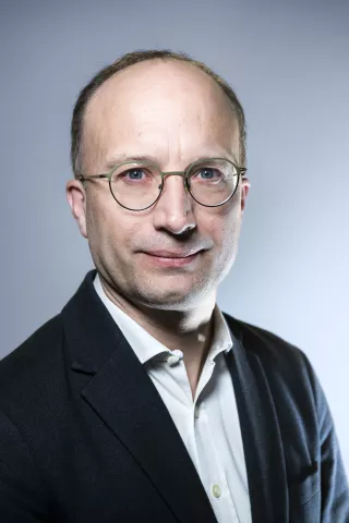 Un homme regarde l'objectif avec un léger sourire