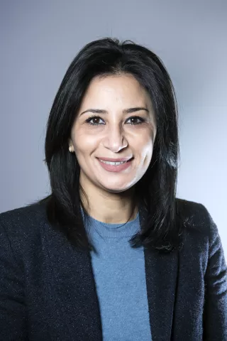 Une femme aux cheveux noires sourit à l'écran