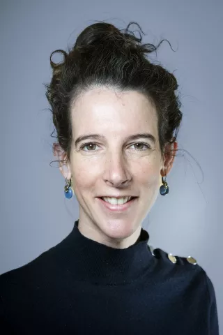 Une femme aux cheveux attachées sourit à l'écran