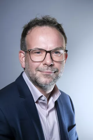 Un homme regarde l'objectif et porte une chemise rose