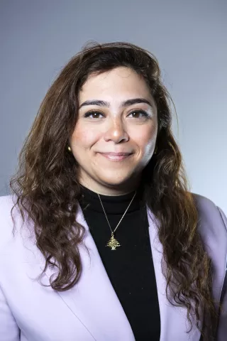 Une femme brune aux cheveux marrons sourit à l'écran