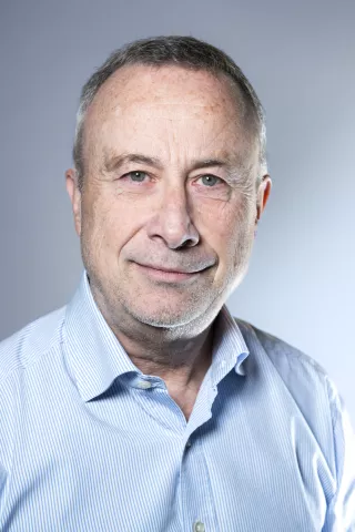 Un homme avec une chemise bleu sourit à l'écran