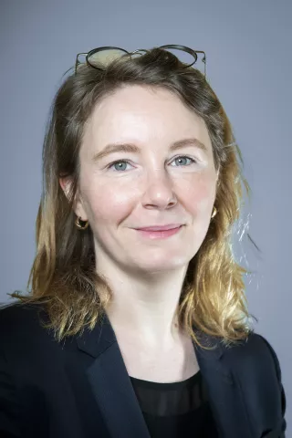 Une femme blonde aux yeux verts sourit à l'écran