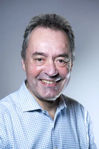 Un homme aux cheveux poivre et sel sourit à l'objectif