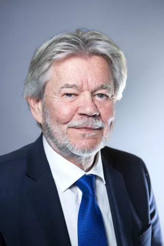 Un homme aux cheveux grisonnant sourit à l'objectif