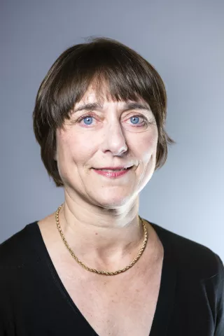 Une femme aux yeux bleus sourit à l'écran